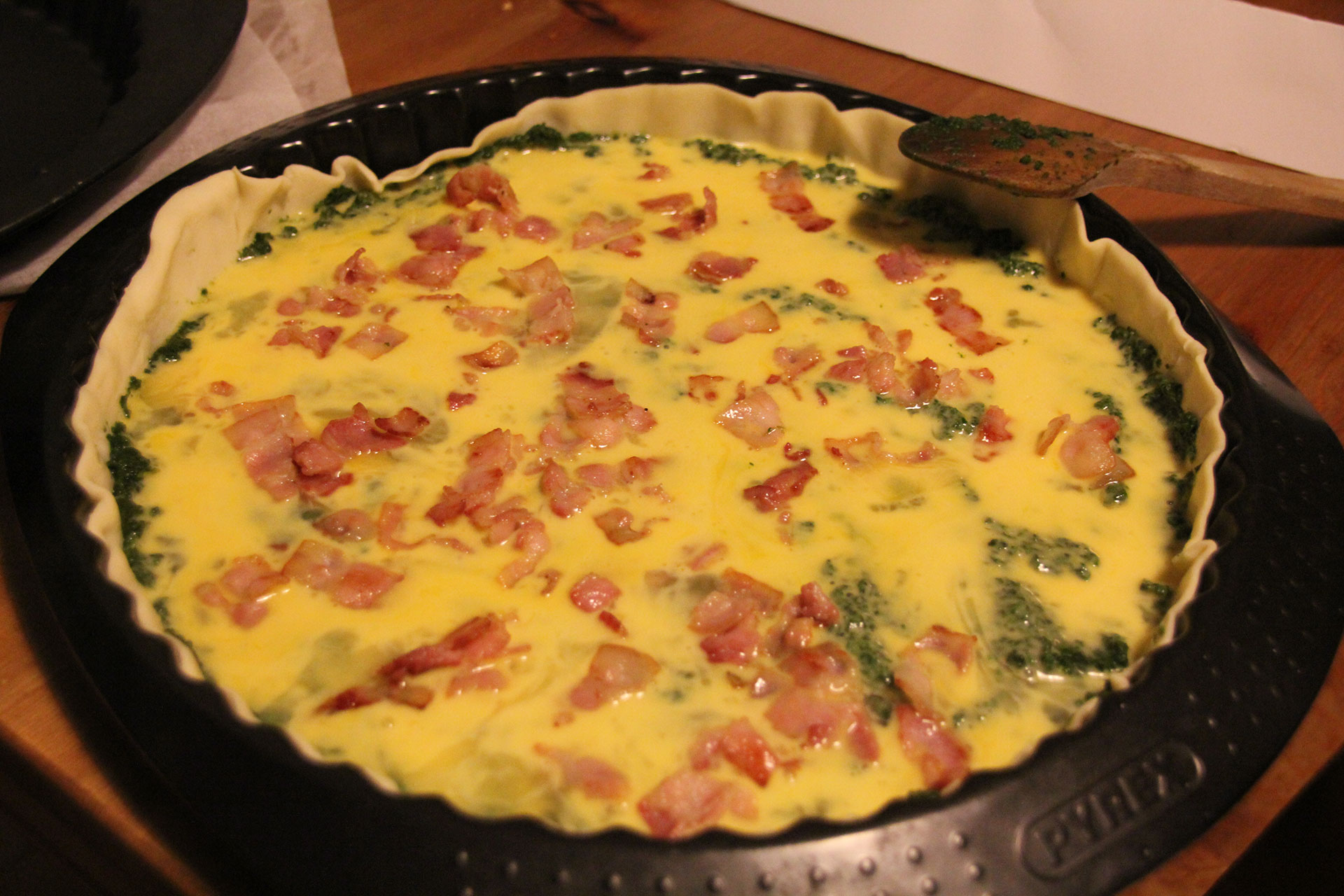 Uncooked quiche with spinach and bacon